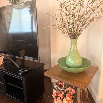Sale Photo Thumbnail #91: Rustic wooden end table featuring a green ceramic vase and bowl set with faux floral branches, shown alongside a black media console.