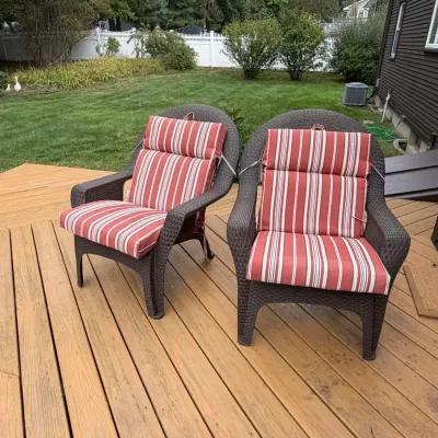 Pair of brown resin wicker patio armchairs styled with vibrant red-and-white striped cushions