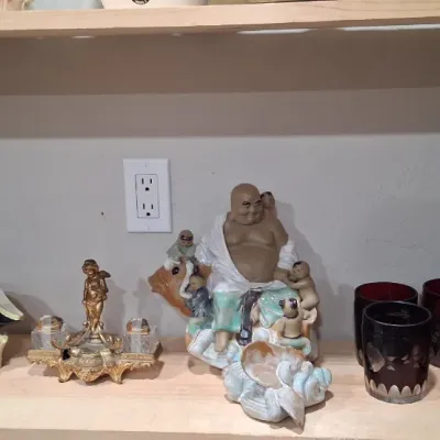Assorted vintage collectibles displayed on a wooden shelf, including Royal Doulton character jugs, an ornate brass inkwell, a ceramic...