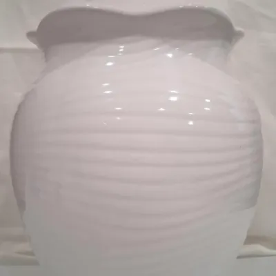 White ceramic lidded ginger jar featuring a ribbed texture and a glossy finish, topped with a spherical finial.