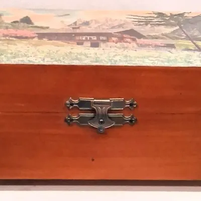 Vintage wooden jewelry or keepsake box featuring a decorative lid illustration of a rustic mountain chalet, complete with a metal latch...