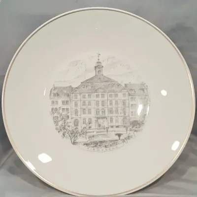 Vintage white porcelain souvenir plate featuring a detailed grey sketch of the Pirmasens town hall in Germany, finished with a delicate...