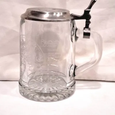 Vintage German glass beer stein featuring an etched design, a starburst-patterned base, and a hinged pewter lid.
