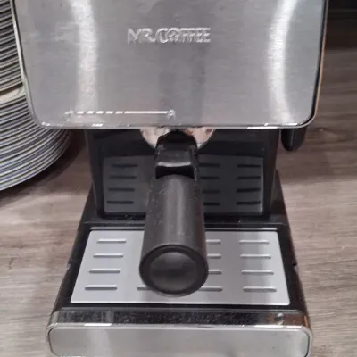 Mr. Coffee steam espresso and cappuccino maker featuring a brushed stainless steel and black plastic exterior with a portafilter attached.