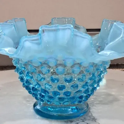 Fenton blue opalescent hobnail glass bowl featuring a ruffled, crimped rim and a footed base, in excellent vintage condition.