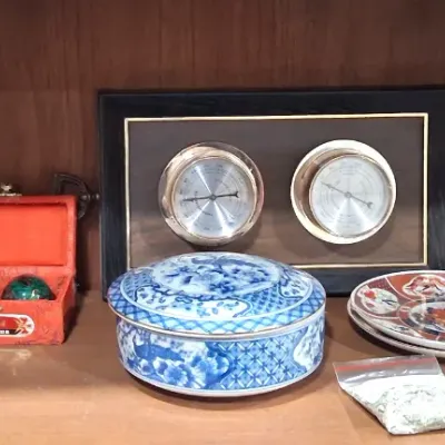 Assorted decorative items on a wooden shelf, including a Himalayan salt lamp, a boxed set of Chinese Baoding balls, a framed dual...