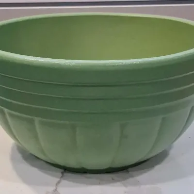 Vintage green McCoy pottery mixing bowl featuring a ribbed upper band and a paneled, pumpkin-like lower body, circa mid-20th century.