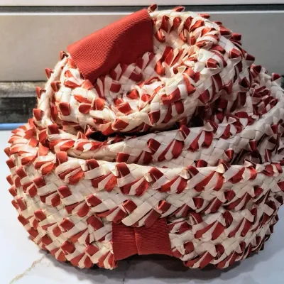Vintage woven straw hat featuring a textured red and cream pattern with red grosgrain ribbon accents.