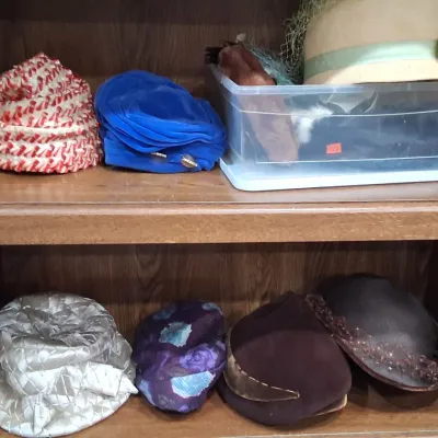 Collection of vintage women's hats from various eras, including a woven red and white turban, a blue velvet hat, and several felt...