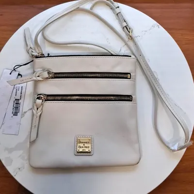 Dooney & Bourke white leather triple-zip crossbody bag with gold-tone hardware, featuring an adjustable shoulder strap and original...
