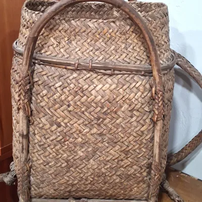 Vintage hand-woven split bamboo backpack basket, featuring a sturdy wooden frame, integrated carrying handles, and woven shoulder straps.