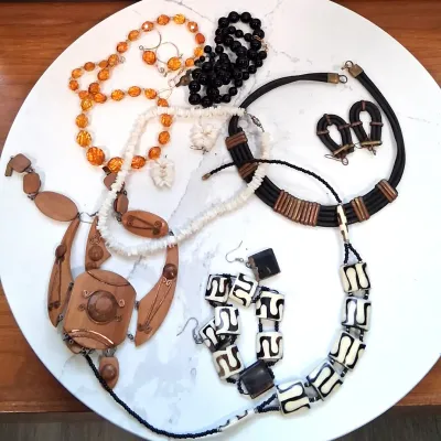 Assortment of vintage statement jewelry, including a carved wooden pendant necklace, a black and white batik-style bone bead necklace...