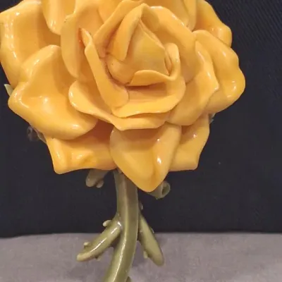 Vintage yellow enamel rose brooch featuring a detailed multi-layered blossom on a thorny green stem, likely mid-century costume jewelry.