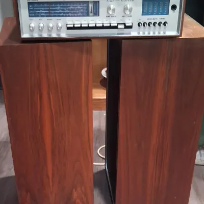 Vintage Supersonic One-Eleven solid state AM/FM stereo receiver in a wood cabinet, paired with two matching wood-cased floor speakers.