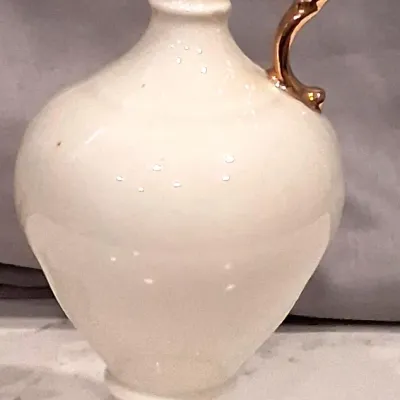 Vintage white porcelain ewer-style vase featuring a gold-gilded handle and trim, set on a pedestal base.