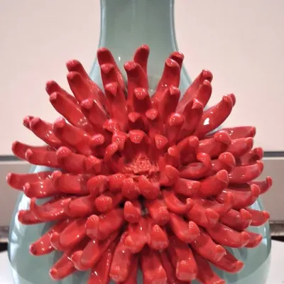 Chinese celadon-glazed porcelain vase featuring a prominent, hand-sculpted red chrysanthemum flower applique on the front.