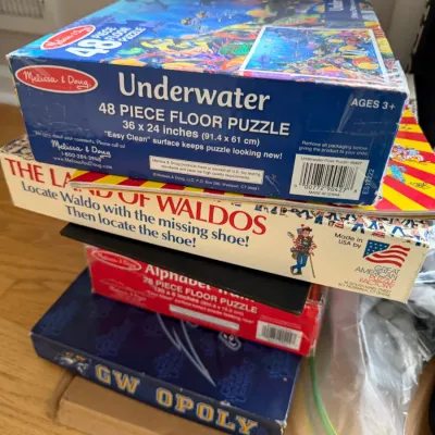Stack of children's games and puzzles, including a Melissa & Doug Underwater 48-piece floor puzzle, a Where's Waldo board...