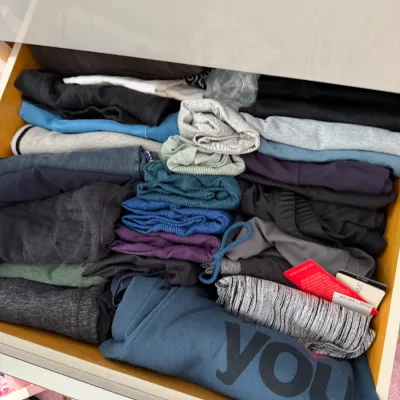 Sale Photo Thumbnail #136: Assorted athletic and casual clothing, including leggings and tops, neatly folded inside a dresser drawer.