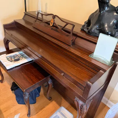 Vintage Carl Fischer spinet piano with a matching wooden bench, featuring carved cabriole legs and a decorative music stand.