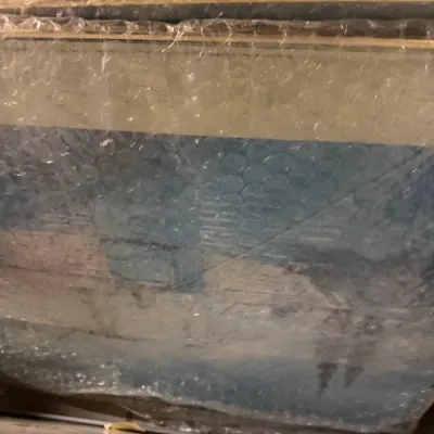 Sale Photo Thumbnail #234: Stack of framed art prints wrapped in protective bubble wrap, showing a winter landscape scene with blue and white tones.