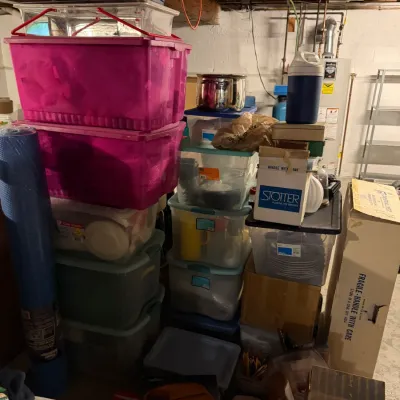 Sale Photo Thumbnail #247: Assorted household goods, storage bins, and kitchenware stacked in a basement storage area.