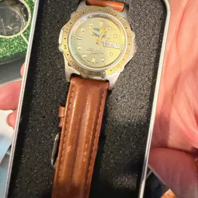 Sale Photo Thumbnail #162: Timberlake quartz watch with a brown leather strap, featuring a day-date window and water resistance up to 30 meters, presented in its original foam-lined tin case.