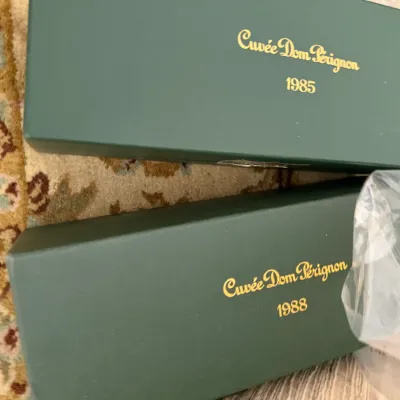 Two green Cuvée Dom Pérignon presentation boxes, one labeled 1985 and the other 1988, featuring gold lettering.