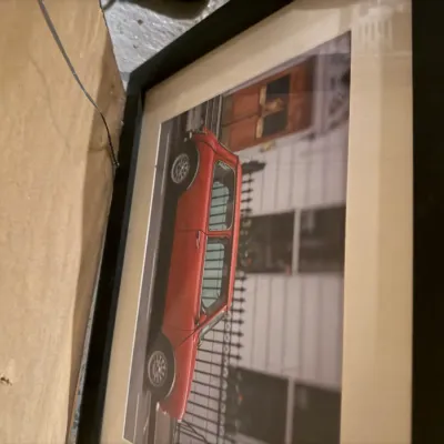 Sale Photo Thumbnail #221: Framed photograph of a classic red Mini Cooper parked on a city street, matted and housed in a simple black frame.