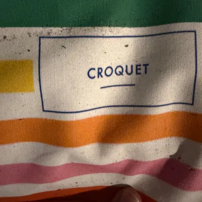 Sale Photo Thumbnail #240: Vintage croquet set carrying bag featuring colorful horizontal stripes and a central logo.