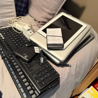 Sale Photo Thumbnail #151: Assorted electronics including two black computer keyboards, a Western Digital My Passport external hard drive, an Apple iPad, and a silver laptop with power cables.