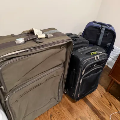 Sale Photo Thumbnail #167: Assorted modern rolling suitcases in olive green, black, and navy blue, showing some wear from travel.