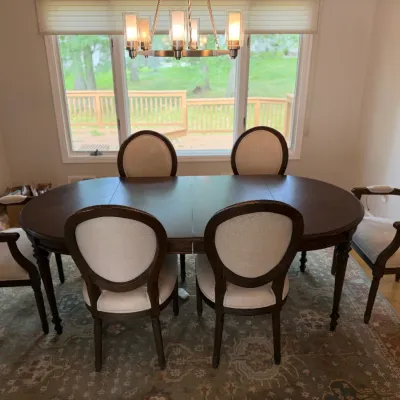 Traditional dark wood dining table with two extension leaves, paired with six upholstered oval-back chairs including two armchairs.