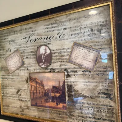 Framed classical music collage featuring Beethoven sheet music, a portrait, and a cityscape print, housed in a dark wood frame with gold...