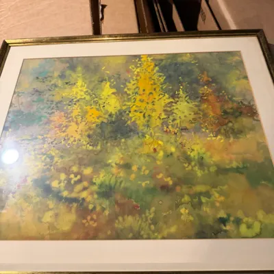Sale Photo Thumbnail #195: Framed impressionist watercolor painting depicting a forest scene with vibrant yellow and green foliage, housed in a gold-toned frame with a white mat.
