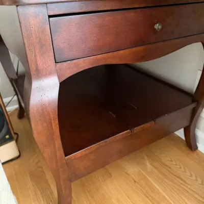 Traditional cherry-finished wooden nightstand featuring a single drawer with a brass pull, an open lower shelf, and elegant cabriole legs.