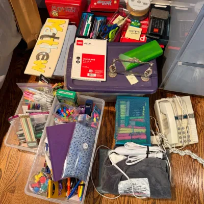 Sale Photo Thumbnail #152: Assortment of office and school supplies, including pens, pencils, notebooks, storage bins, a landline telephone, and a heating pad.