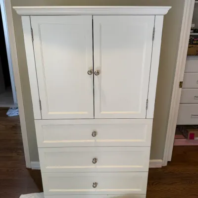 Sale Photo Thumbnail #148: White painted wooden armoire featuring a double-door upper cabinet and four spacious lower drawers with silver-toned round pulls.