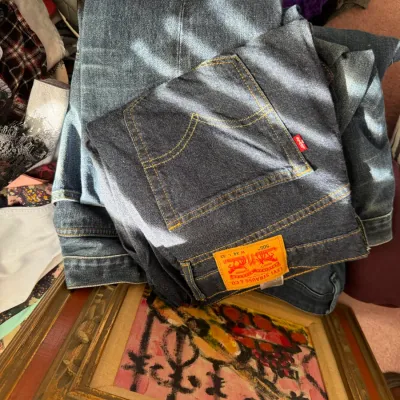 Sale Photo Thumbnail #126: Levi Strauss & Co. 505 blue jeans, size 34 x 32, shown folded alongside other clothing items and a framed painting.