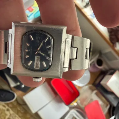 Vintage Seiko Hi-Beat automatic watch featuring a chunky square stainless steel case, dark dial, and day-date window, showing moderate...