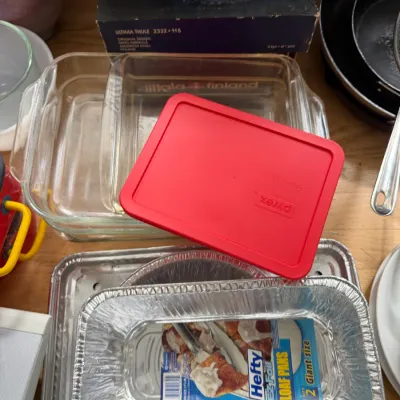 Assorted kitchenware including clear glass baking dishes, a red-lidded Pyrex container, and a package of Hefty EZ Foil loaf pans.
