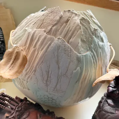 Contemporary studio art pottery vessel featuring a textured, multi-layered surface with organic leaf and bark patterns in muted earth tones.