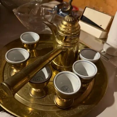 Sale Photo Thumbnail #178: Vintage brass Turkish coffee set featuring an engraved long-handled pot, matching round tray, and six small porcelain-lined brass cups.