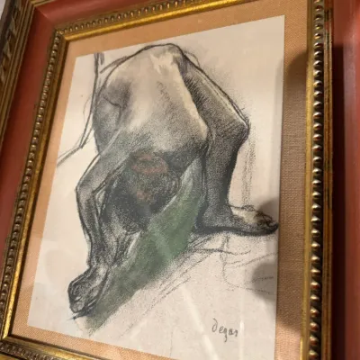 Sale Photo Thumbnail #197: Framed charcoal and pastel sketch of a bending nude figure, signed Degas, housed in an ornate gold-gilded and reddish-brown wooden frame.