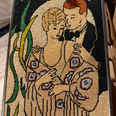 Sale Photo Thumbnail #199: Framed needlepoint art depicting a vintage-style "New Yorker" magazine cover illustration of a couple in formal attire.