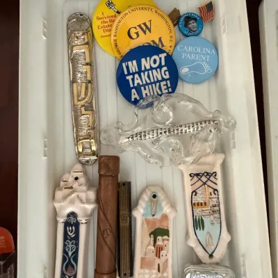 Collection of vintage Judaica items, including several mezuzah cases in ceramic, metal, and glass, alongside various novelty pinback...