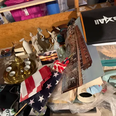 Sale Photo Thumbnail #175: Assorted vintage collectibles and home goods, including a brass Turkish coffee set, porcelain figurines, small American flags, and a light blue rotary telephone.