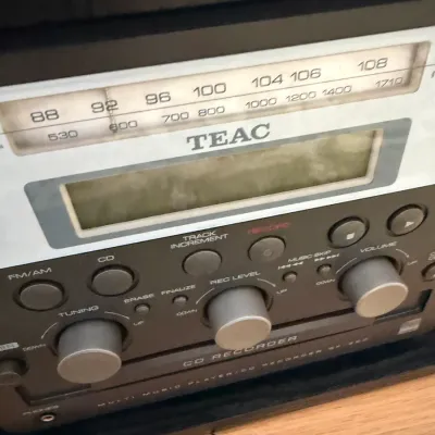 TEAC multi music player and CD recorder, featuring an AM/FM radio tuner dial, digital display screen, and silver control knobs.