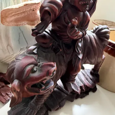 Carved dark wood statue depicting a Chinese deity or warrior riding a mythical beast, possibly a Qilin or Foo Dog, showing detailed...