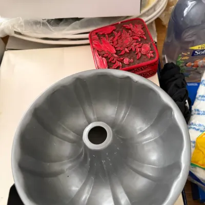 Vintage aluminum Bundt cake pan shown alongside a small red cinnabar-style trinket box with floral carvings.