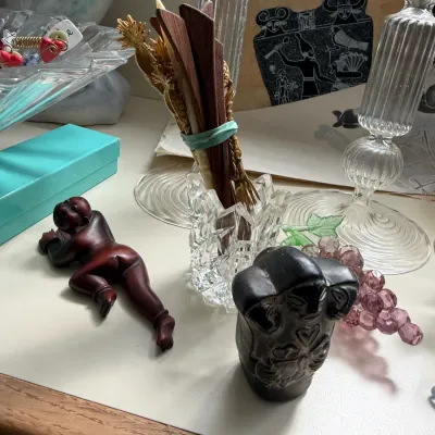 Assorted small decorative items, including a carved wooden figure of a reclining person, a small stone carving, a crystal toothpick...